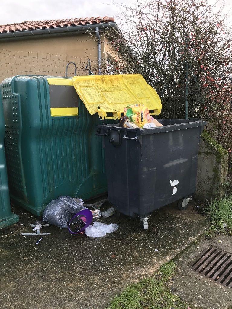 Bac jaune ouvert et sac de déchets posé au sol.